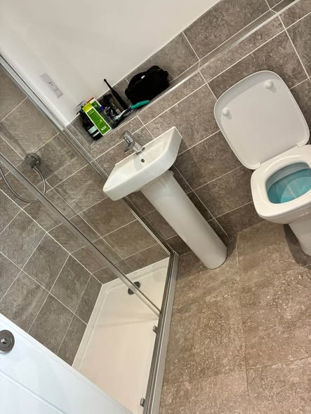 A bathroom with grey tiles, a white basin, and a clean shower tray.