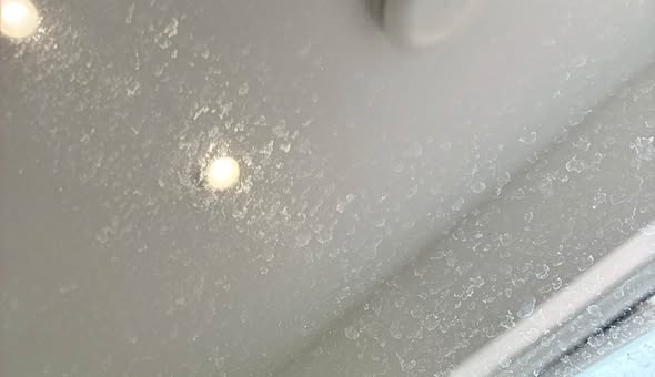 Shower glass covered in hard-water spots before a clean.