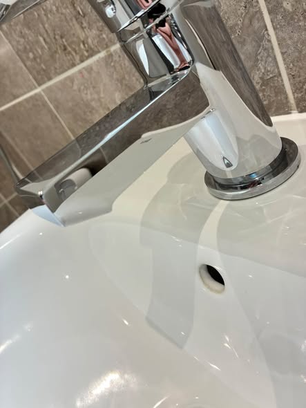 A chrome mixer tap shining on a white basin.